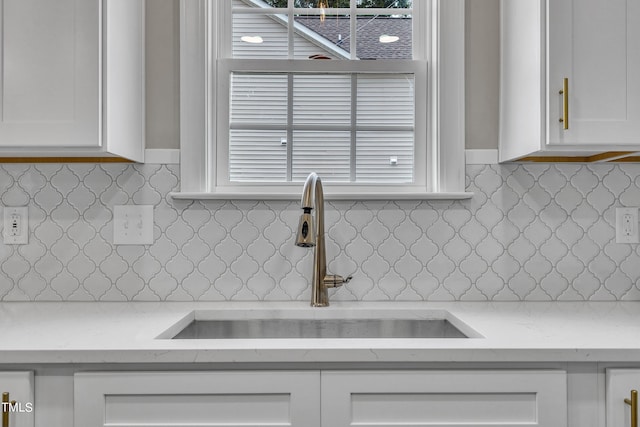 kitchen with decorative backsplash, sink, and white cabinets