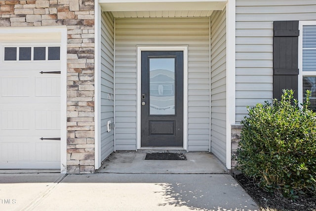 entrance to property featuring stone siding and an attached garage