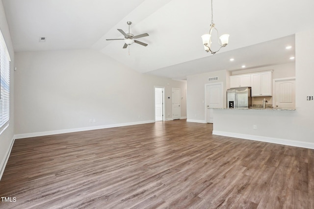 unfurnished living room with vaulted ceiling, wood finished floors, visible vents, and baseboards