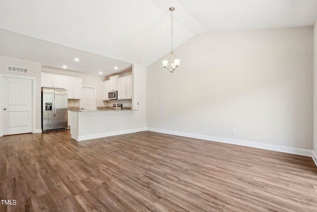 unfurnished living room featuring lofted ceiling, visible vents, wood finished floors, a chandelier, and baseboards