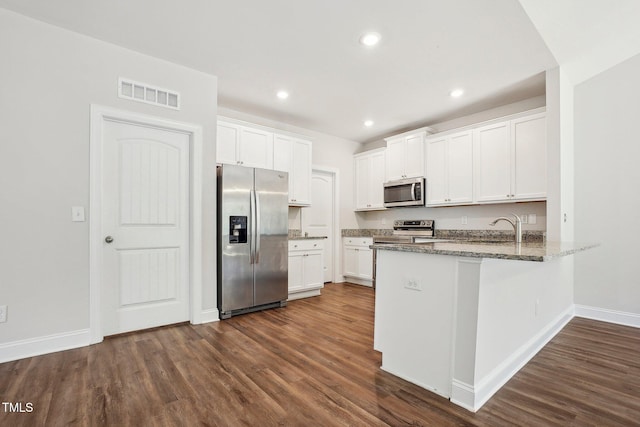 kitchen featuring visible vents, white cabinets, a peninsula, stainless steel appliances, and stone counters