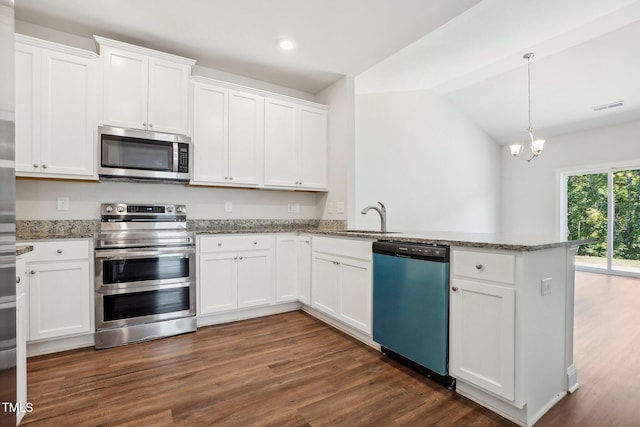 kitchen with dark wood-style floors, stainless steel appliances, white cabinetry, a sink, and a peninsula