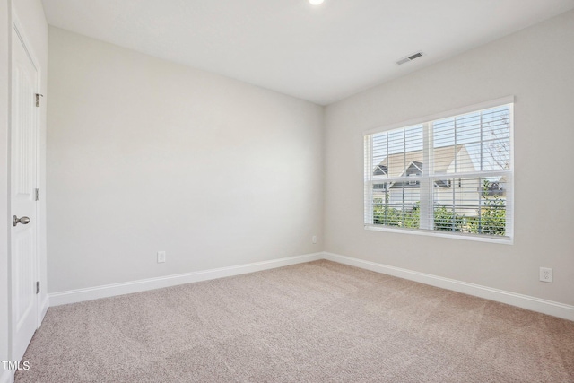 empty room featuring baseboards, visible vents, and light colored carpet