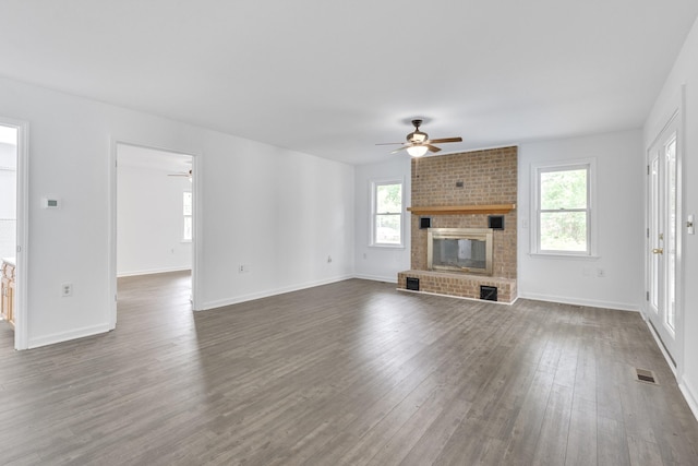 unfurnished living room with ceiling fan, a fireplace, and dark wood-type flooring