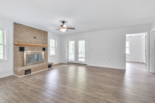 unfurnished living room with a brick fireplace, a wealth of natural light, ceiling fan, and hardwood / wood-style flooring