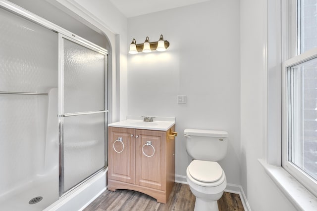 bathroom featuring wood-type flooring, vanity, toilet, and an enclosed shower