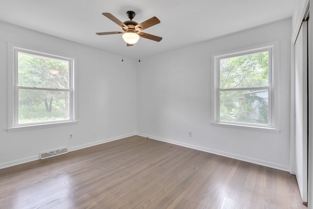 spare room with a healthy amount of sunlight, ceiling fan, and hardwood / wood-style flooring