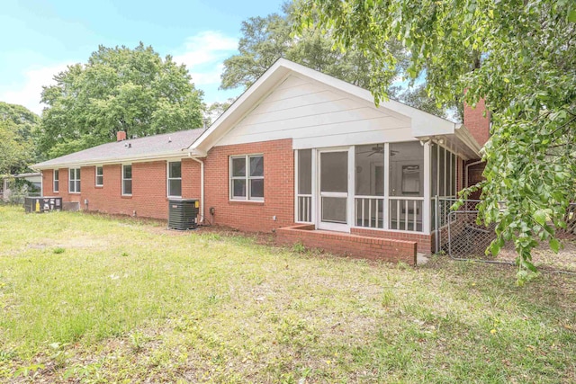 back of house featuring a lawn, a sunroom, and central air condition unit