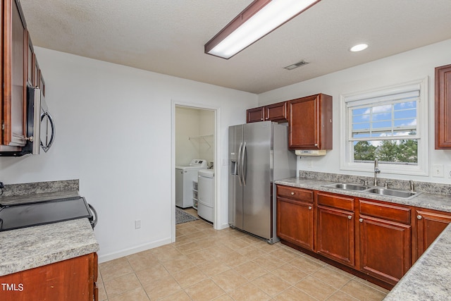 kitchen with stainless steel appliances, sink, washing machine and dryer, light tile patterned floors, and a textured ceiling