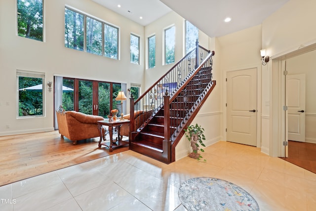 stairway featuring a towering ceiling, plenty of natural light, and wood-type flooring