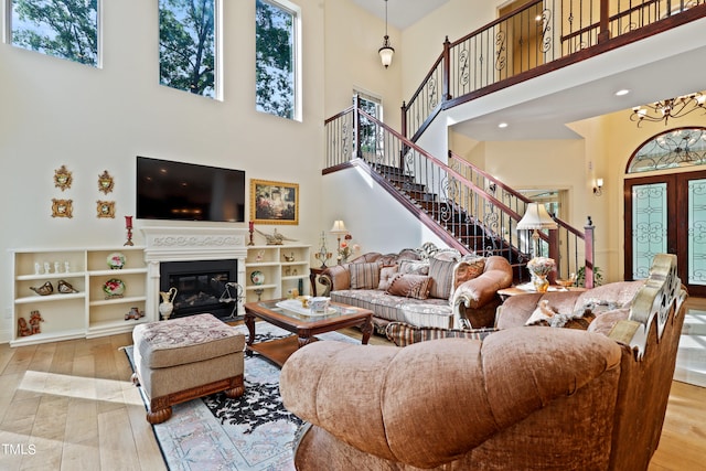 living room with light hardwood / wood-style flooring, a high ceiling, a chandelier, and plenty of natural light