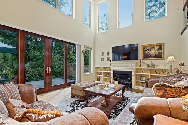 living room featuring light hardwood / wood-style floors, a towering ceiling, and built in shelves