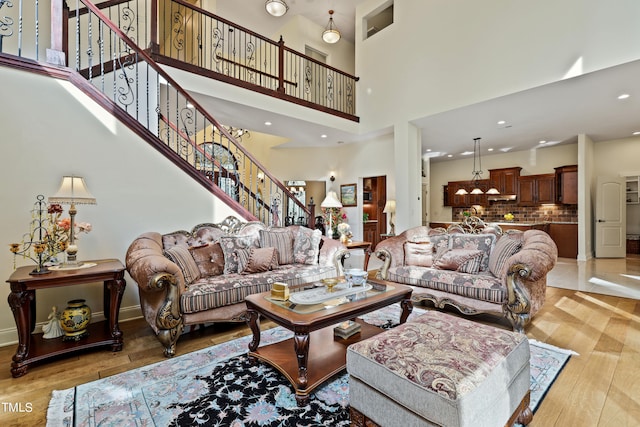 living room featuring light wood-type flooring and a towering ceiling