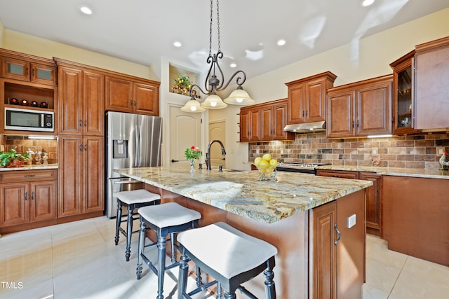 kitchen with a kitchen island with sink, stainless steel appliances, sink, and decorative backsplash