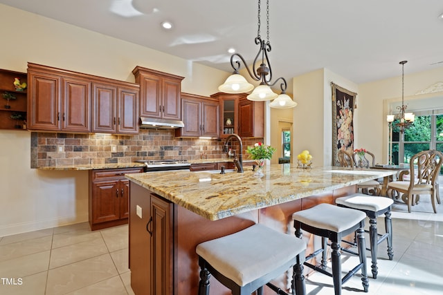 kitchen featuring light stone counters, kitchen peninsula, a breakfast bar, stainless steel range oven, and decorative backsplash