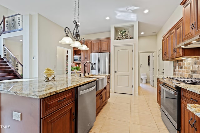 kitchen featuring pendant lighting, sink, a large island with sink, stainless steel appliances, and decorative backsplash