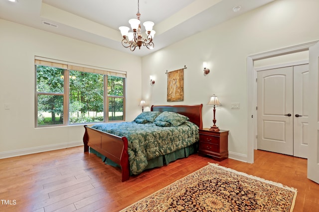 bedroom featuring a notable chandelier, a tray ceiling, and hardwood / wood-style floors