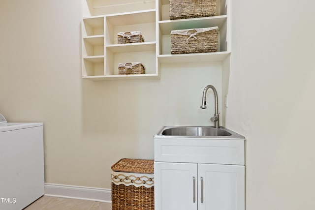 clothes washing area featuring separate washer and dryer, sink, and cabinets