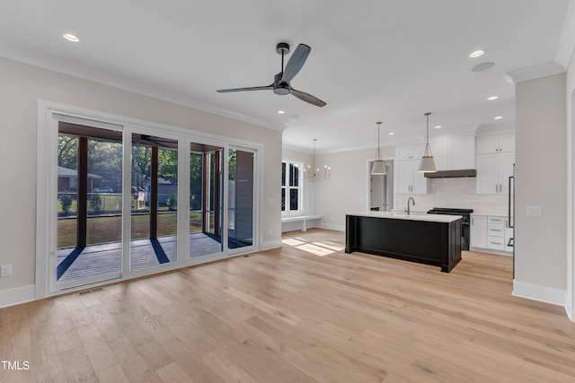 interior space with light wood-style flooring, ceiling fan with notable chandelier, baseboards, and ornamental molding