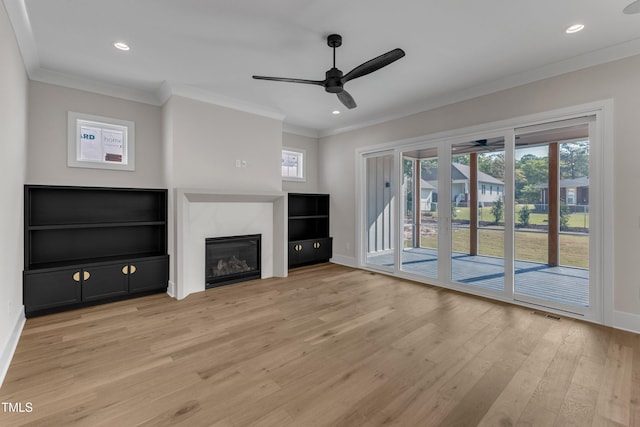 unfurnished living room featuring crown molding, light wood-type flooring, a ceiling fan, and baseboards