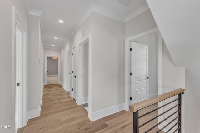 hall with light wood-style floors, baseboards, ornamental molding, and visible vents