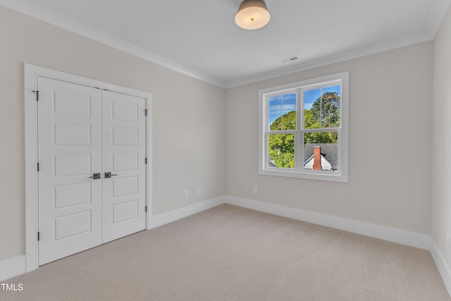 carpeted spare room with visible vents, baseboards, and crown molding