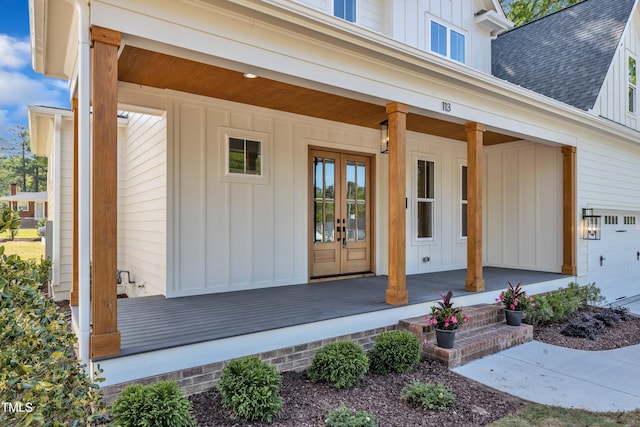 entrance to property with board and batten siding, french doors, a porch, and roof with shingles