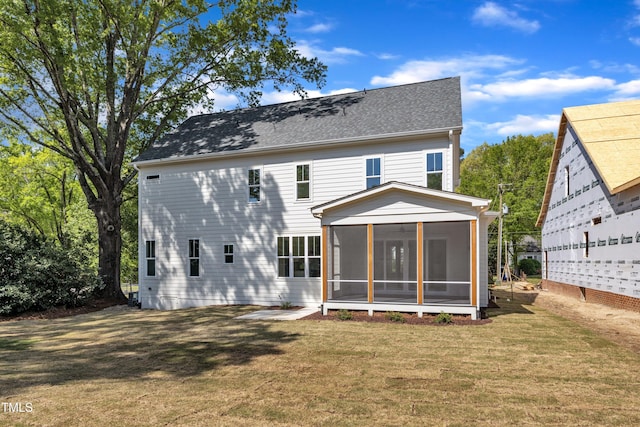 rear view of house featuring a sunroom, a lawn, and roof with shingles