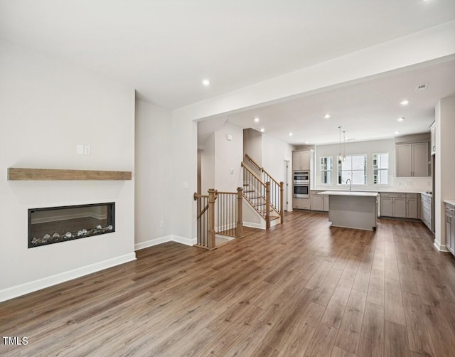 unfurnished living room featuring wood-type flooring and sink