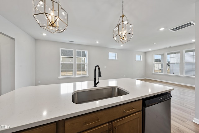 kitchen with sink, decorative light fixtures, a chandelier, stainless steel dishwasher, and plenty of natural light