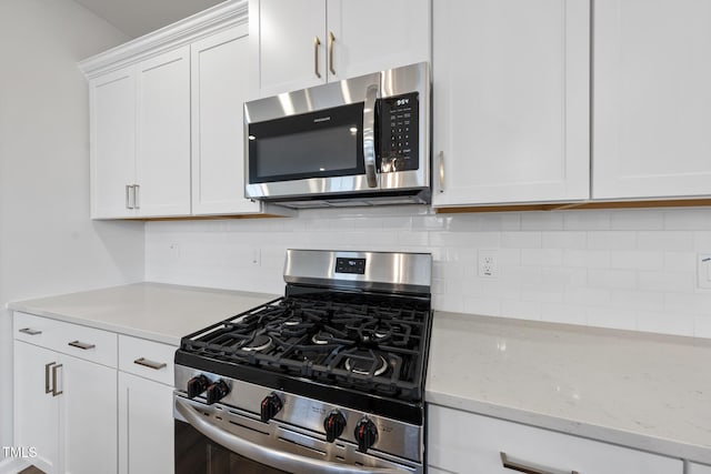 kitchen with white cabinetry, tasteful backsplash, light stone countertops, and appliances with stainless steel finishes