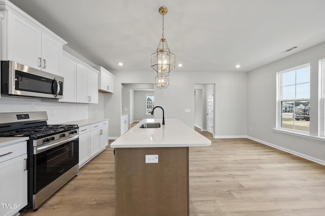 kitchen featuring white cabinetry, stainless steel appliances, sink, and a center island with sink