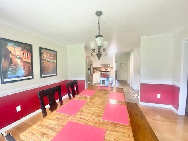 dining space featuring a notable chandelier, crown molding, and hardwood / wood-style floors