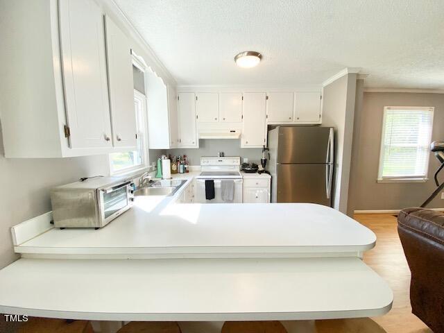 kitchen featuring sink, light hardwood / wood-style flooring, white cabinetry, white electric range, and stainless steel refrigerator