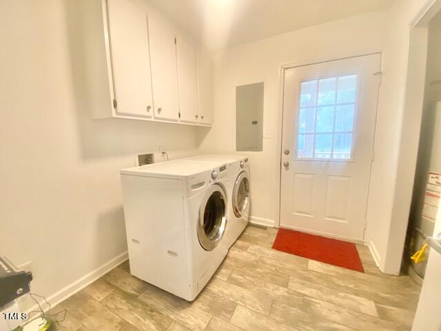 laundry area with electric panel, washer and dryer, and cabinets