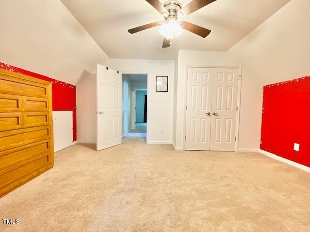 unfurnished bedroom with lofted ceiling, ceiling fan, and light colored carpet