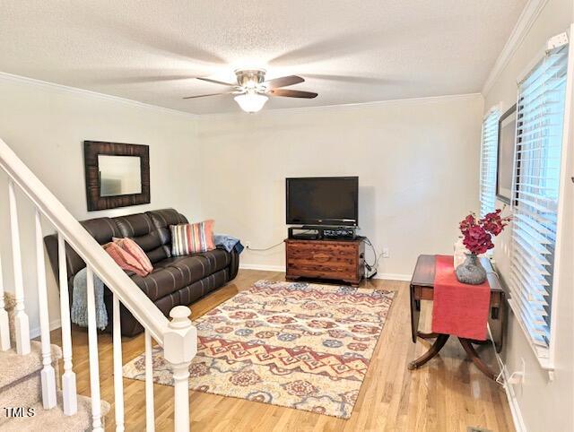 living room featuring ceiling fan, hardwood / wood-style flooring, crown molding, and a textured ceiling