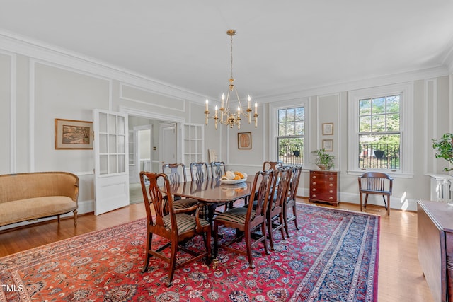 dining area with ornamental molding, light hardwood / wood-style flooring, and a chandelier