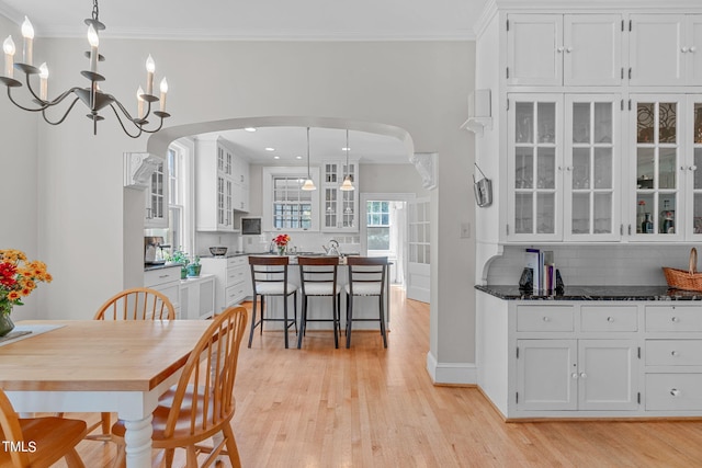 dining room featuring a notable chandelier, ornamental molding, and light wood-type flooring