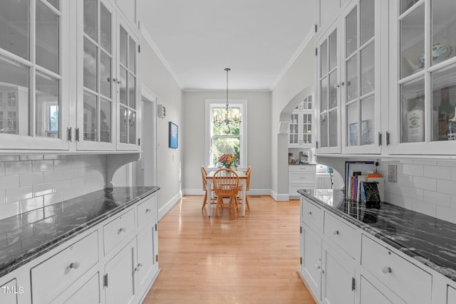 kitchen with backsplash, decorative light fixtures, and dark stone counters