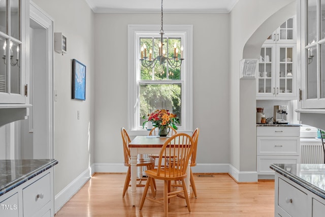 dining space with ornamental molding, light hardwood / wood-style flooring, and a chandelier