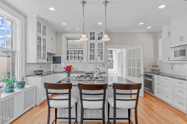 kitchen with appliances with stainless steel finishes, pendant lighting, decorative backsplash, and white cabinets