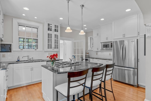 kitchen with a center island, white cabinetry, stainless steel appliances, and pendant lighting