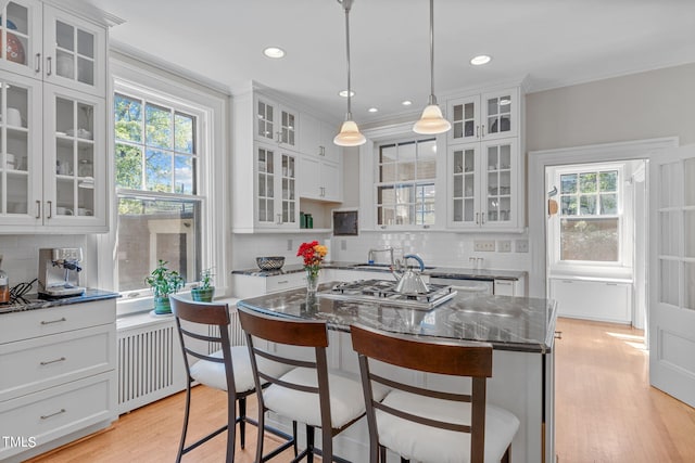 kitchen with white cabinetry, a breakfast bar area, dark stone countertops, and backsplash