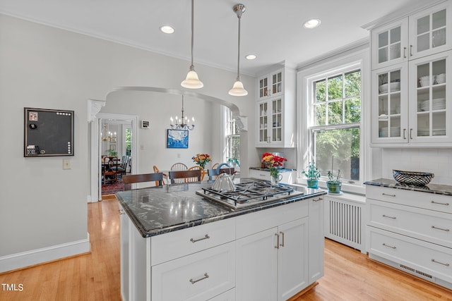 kitchen featuring radiator, pendant lighting, stainless steel gas stovetop, white cabinetry, and light hardwood / wood-style floors