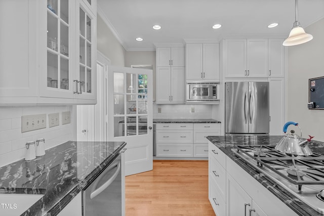 kitchen with white cabinets, backsplash, dark stone countertops, pendant lighting, and stainless steel appliances