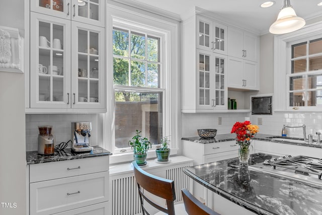 kitchen with white cabinetry, hanging light fixtures, backsplash, and dark stone countertops