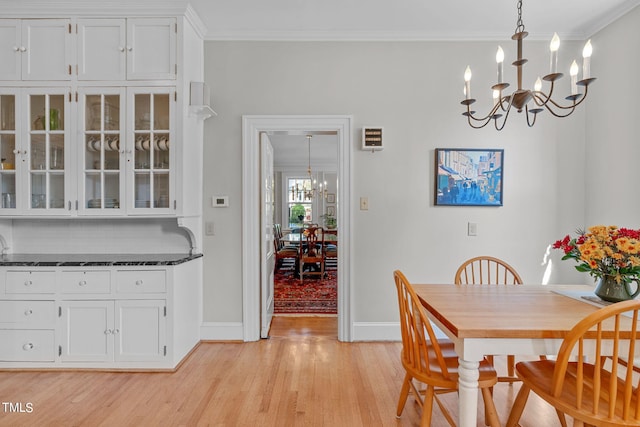 dining space with light hardwood / wood-style flooring, a chandelier, and crown molding