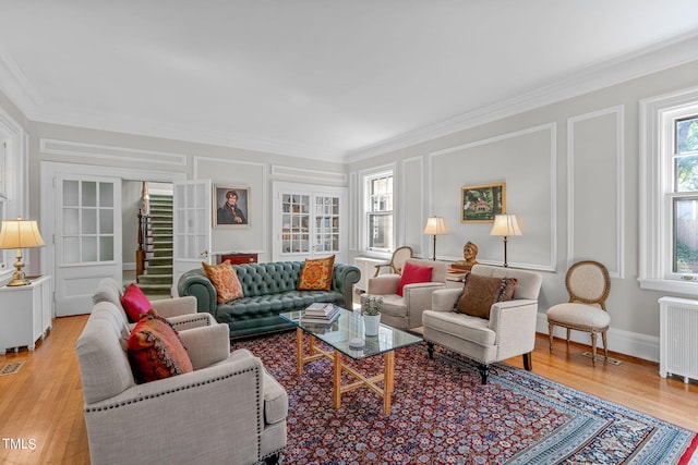 living room featuring radiator, crown molding, and light wood-type flooring