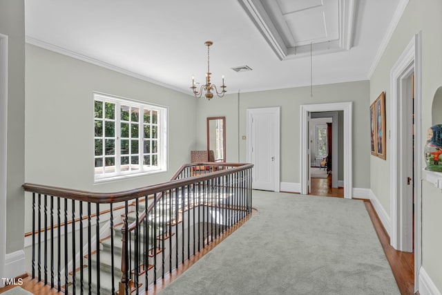 hall with light hardwood / wood-style floors, an inviting chandelier, and ornamental molding